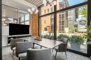 a dining room with a large window and a table with chairs and a television at The Can Plant Residences at Pearl, San Antonio
